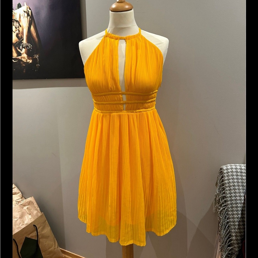 Yellow halter neck dress with pleated skirt and cut out details